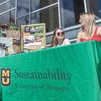Lakelen Murphy and Bella Kamplain sit at a table doing outreach for Sustain Mizzou