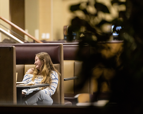 Student laughing and eating at campus dining location.